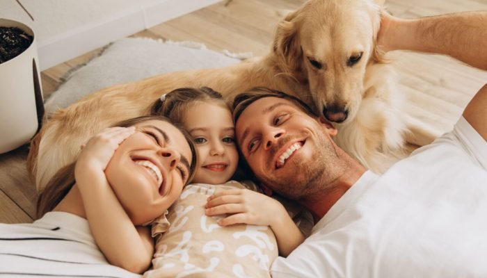 smiling-happy-family-beautiful-mother-father-cute-little-daughter-hugging-with-golden-retriever-1-sc.jpeg