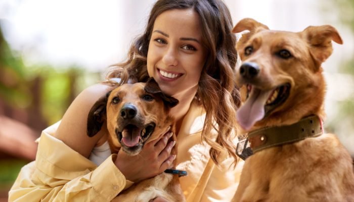 young-charming-smiling-girl-is-resting-while-walking-park-with-two-golden-dogs-girl-hugs-her-pets-lo.jpeg